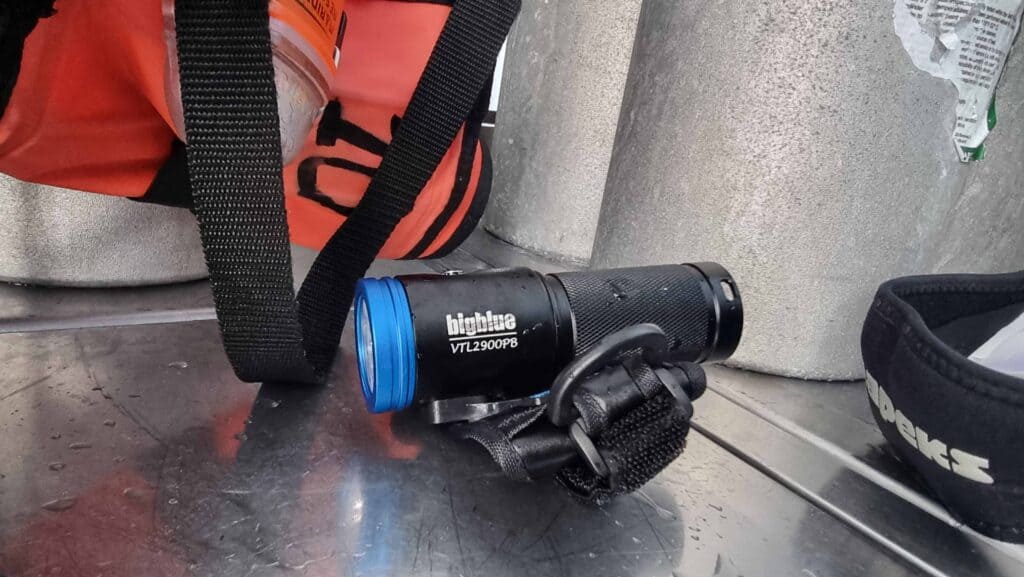 dive torch in front of dive equipment on silver bench